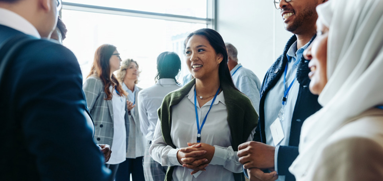 Un groupe de personnes se mêle dans une pièce bien éclairée, vêtues de tenues professionnelles et portant des badges nominaux