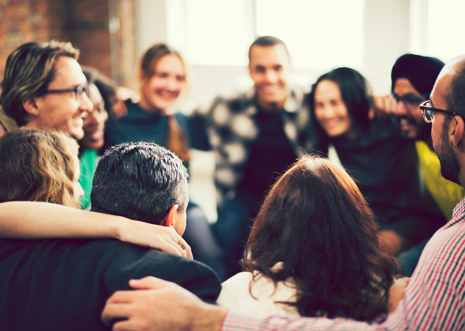 Une équipe en cercle se tenant par les épaules.