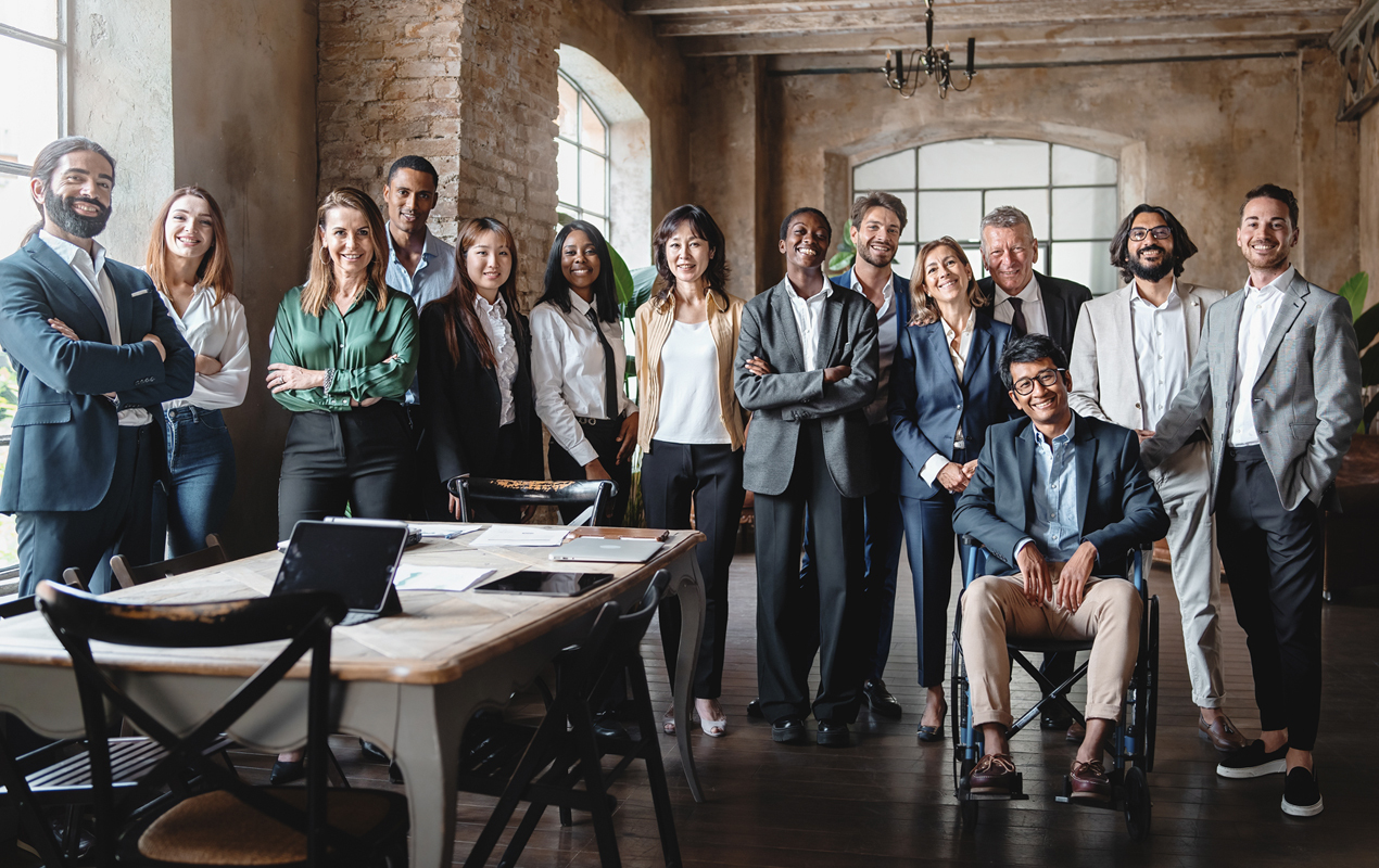 Une équipe diversifiée d’âges, de races, de genres et de capacités mixtes faisant face à la caméra.